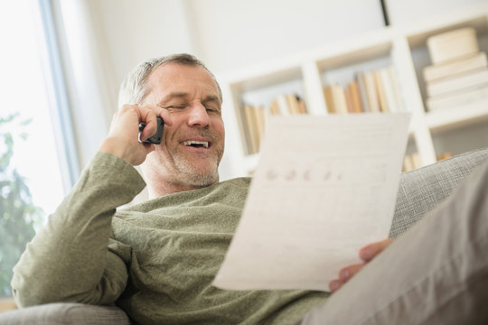 Older Caucasian man talking on telephone reading paperwork