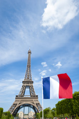 Fototapeta na wymiar French tricolour flag flying in bright blue sky on a summer day in front of the Eiffel Tower in Paris, France