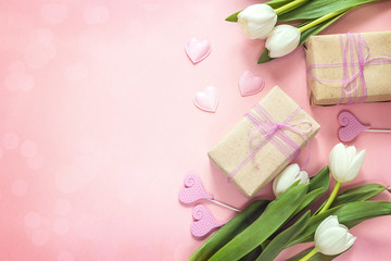 White tulips, hearts and gift boxes on pink background. Happy mother's day concept.