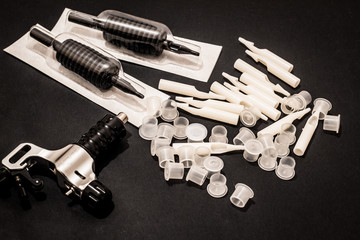 tattoo machine caps needles and grips on black background