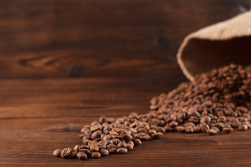 Coffee is poured from a burlap on a wooden background