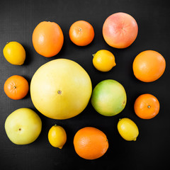 Citrus fruits, vitamin mix on black background. Flat lay, top view. Tropical summer mix grapefruit, orange, mandarin, lime