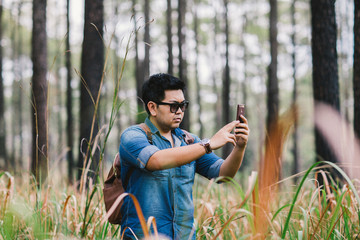A man with his mobile smart phone searching for reception signal in the forest.