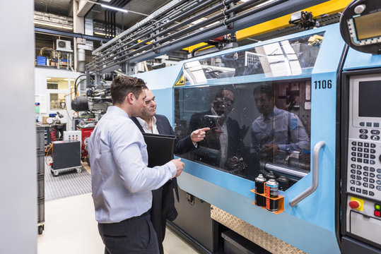 Two men talking about machines in factory shop floor