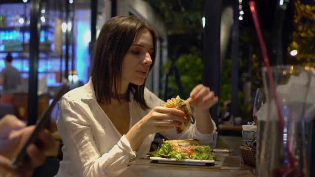 Young woman eating tasty meal in cafe at night
