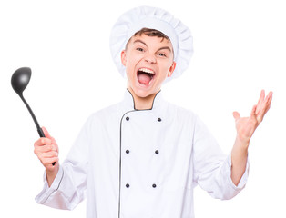 Cheerful handsome teen boy wearing chef uniform. Portrait of a happy cute male child cook with black ladle, isolated on white background. Food and cooking concept.