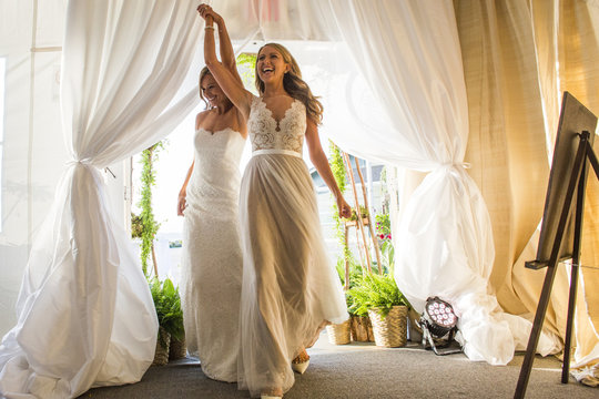 Caucasian brides walking through curtain