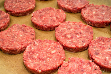 Fresh raw beef burger patties on paper background