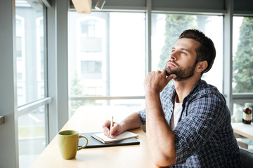 Thinking man in office coworking while writing notes