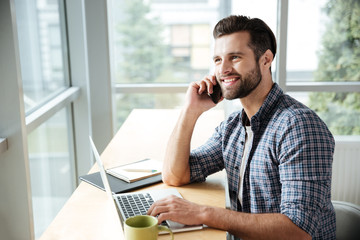 Naklejka premium Happy man in office coworking talking by phone.