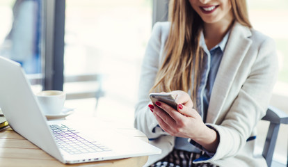 Obraz premium Woman Working on Laptop and Using Phone