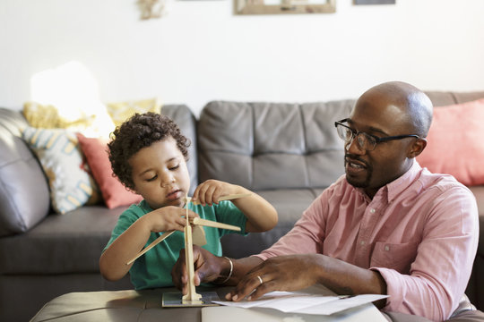 Father and son building model windmill in living room