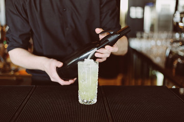 Fototapeta na wymiar Barman's hands in bar interior making non-alcohol cocktail