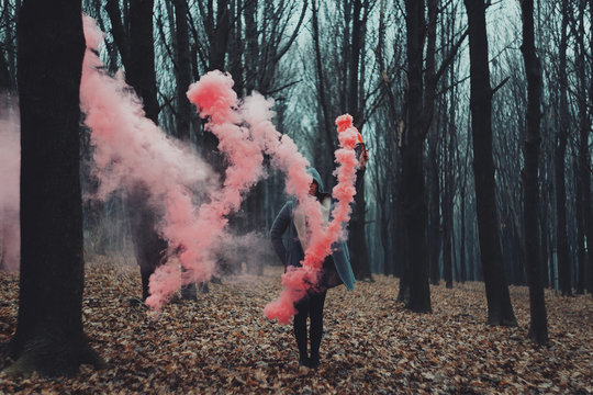 Woman holds up red smoke flare to signal for help in the middle of nature