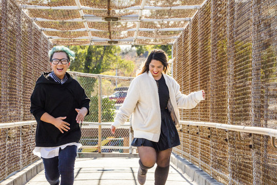 Smiling Asian women running on footbridge
