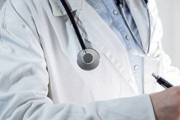 Medical doctor on white background holding a stethoscope. Focus on the stethoscope.