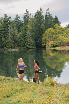 Women stretching legs near lake