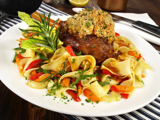 Lammhaxe mit Kräuterkruste auf Nudeln mit Gemüse