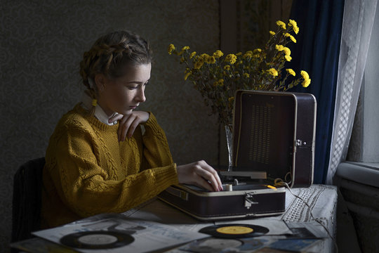 Woman playing vinyl records on portable turntable