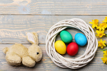 rabbit toy, colorful easter eggs in wreath with yellow narcissus
