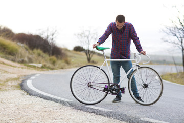 Fototapeta premium Cyclist man riding fixed gear sport bike in sunny day on a mountain road