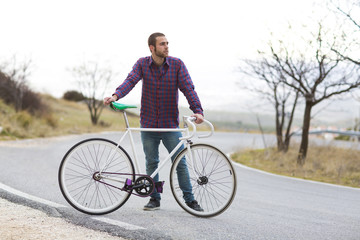 Obraz premium Cyclist man riding fixed gear sport bike in sunny day on a mountain road