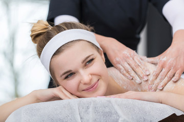 Fototapeta na wymiar Woman getting exfoliating salt scrub massage at beautician's
