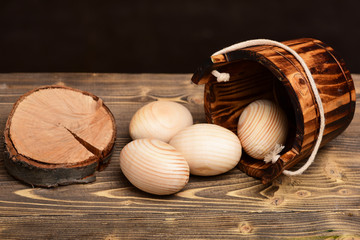 easter beige wood eggs in wooden bucket near tree stump