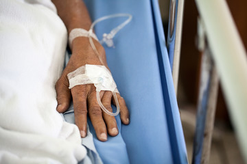 Fototapeta na wymiar Closeup of saline intravenous drip in old woman patient hand