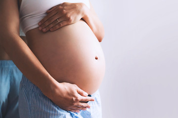 Close-up pregnant woman's belly on white background