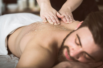 Obraz na płótnie Canvas Man relaxing during a salt scrub beauty therapy