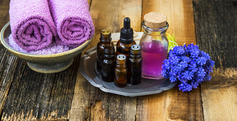 Fototapeta na wymiar Spa setting.Oil bottles with purple flowers and soft towels on wooden rustic background