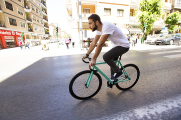 Cyclist man riding fixed gear sport bike in sunny day on a city
