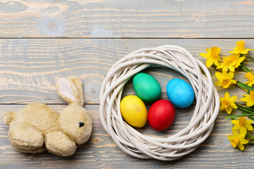 rabbit toy, colorful easter eggs in wreath with yellow narcissus
