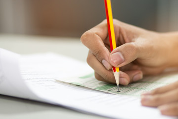 students hand testing doing examination with pencil drawing selected choice on answer sheets in school exam at  college