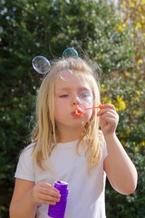 adorable school age girl blowing bubbles outside