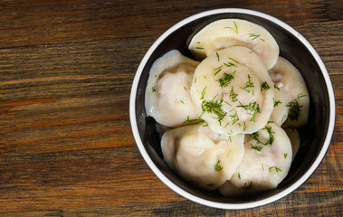 Meat dumplings - russian pelmeni, ravioli with meat on a wooden background. top view.