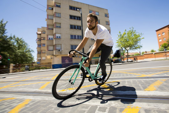 Cyclist man riding fixed gear sport bike in sunny day on a city