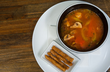 Coconut milk soup with chicken and mushrooms, Thai traditional dish on a wooden background with copy space. top view