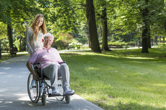 Woman with grandfather on a wheelchair in the park