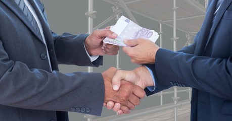 Midsection of business people shaking hands while passing money