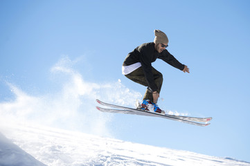 Freestyle ski jumper with crossed skis in snowy mountains