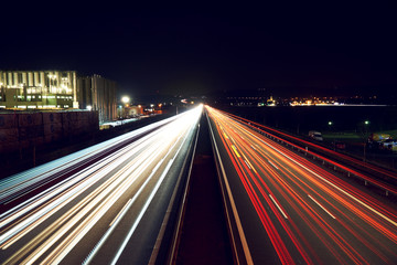 Light trails on highway with a industry building - slightly toned.