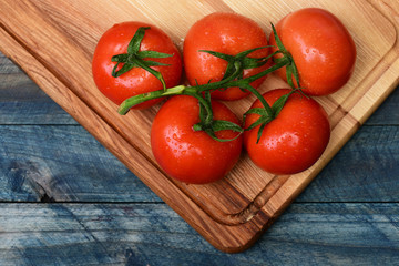 Tomatoes on vine on board on brown vintage wooden background © be free