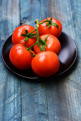 tomatoes on vine on plate on blue vintage wooden background