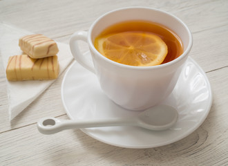 A cup of tea with lemon on a wooden table