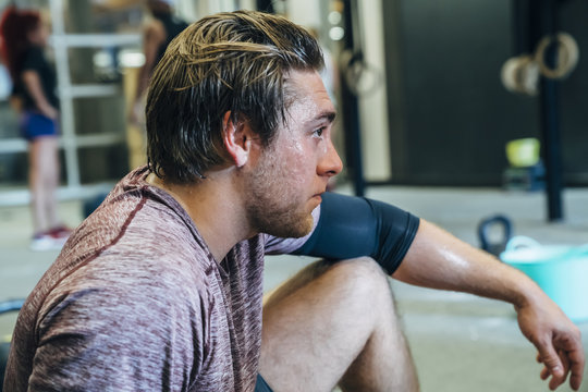 Sweating Caucasian man resting in gymnasium