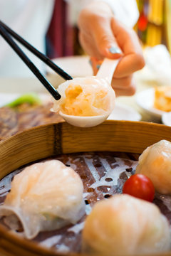 Girl taking shrimp dumpling with chopsticks