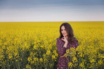 Naklejka na ściany i meble Spring portrait of a woman in the rapeseed field