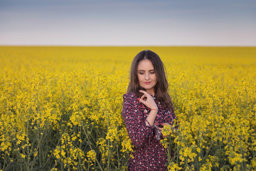 Naklejka na ściany i meble Spring portrait of a woman in the rapeseed field